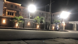 Vista nocturna de una calle con un edificio que tiene una entrada porticada, iluminada por farolas.