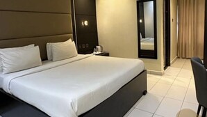 Una habitación de hotel moderna con una cama grande, una mesita de noche, un espejo y una silla.