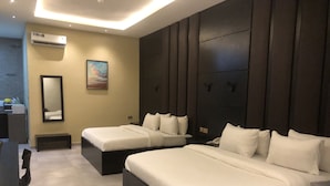 Una habitación de hotel moderna con dos camas, un espejo grande, un equipo de aire acondicionado y un cuadro en la pared.