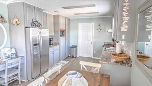 Una cocina equipada con refrigerador, estufa y microondas. Hay una mesa de comedor con sillas.
