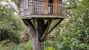 A treehouse with a wooden deck, two doors, and a window. - 6 bedroom accommodation in East Grinstead (East Grinstead)