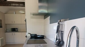 A modern kitchen with stainless steel appliances, a microwave, a frying pan, and a sink. - La Maison Eclusière - Genelard (GENELARD)