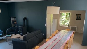 A dining area with a long table, chairs, a sofa, and a television. - La Maison Eclusière - Genelard (GENELARD)
