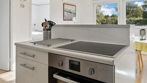 Uma cozinha moderna com fogão embutido, um escorredor de louça e um porta-utensílios de aço inoxidável.