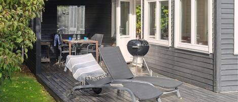 Un espace extérieur abrité comprenant une table à manger, des chaises et un barbecue.