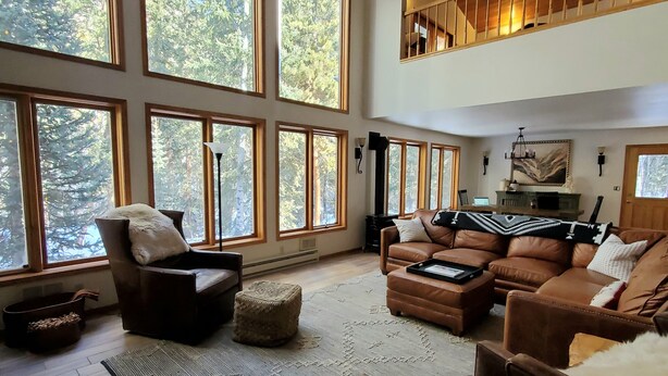 A spacious living room with large windows, a high ceiling, and a cozy seating area.