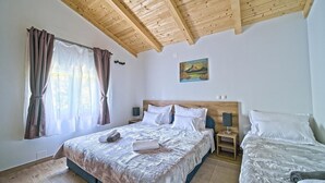 Un dormitorio con techo de madera, una cama con colcha estampada, una mesita de noche con lámpara y un cuadro en la pared.
