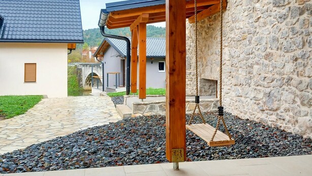 Un muro de piedra con un conjunto de columpios de madera en un patio.