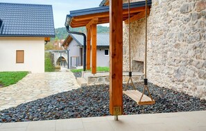 Un muro de piedra con un conjunto de columpios de madera en un patio.