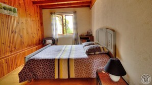 Une pièce aux murs lambrissés, comprenant un lit, une table de chevet, une lampe et une fenêtre avec des rideaux.