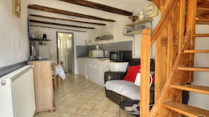 Une cuisine chaleureuse avec des poutres en bois, un coin repas avec une table et des chaises, et un escalier.