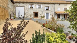 Un bâtiment en pierre doté d’une cour, d’un espace de repos abrité et de plantes en pot.