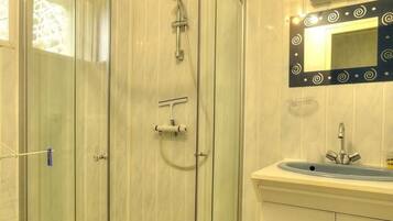Une salle de bain moderne avec une douche à parois de verre, un lavabo avec un miroir et un revêtement de sol carrelé.