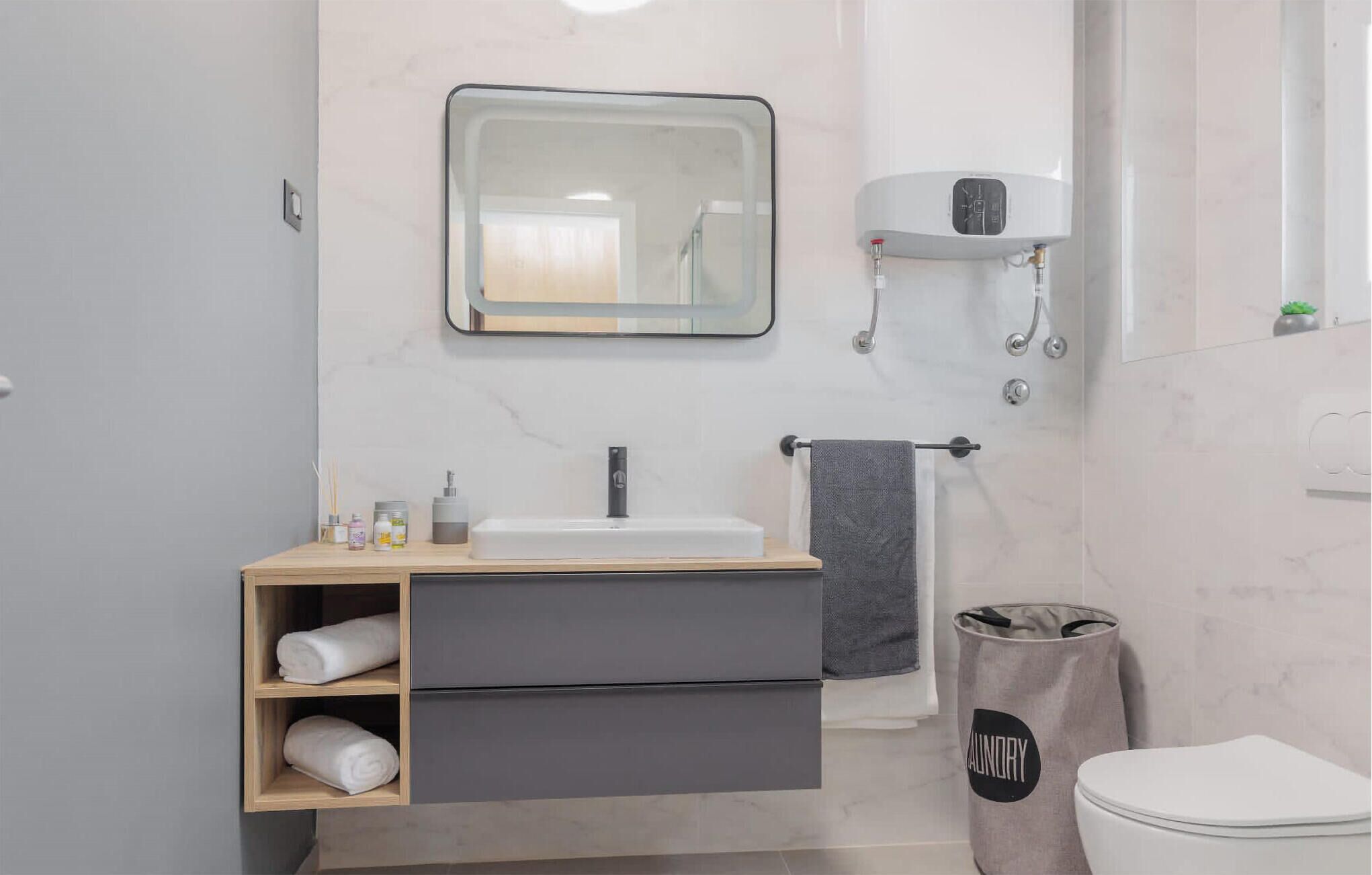 A modern bathroom with a vanity, sink, mirror, towel rack, and a toilet.