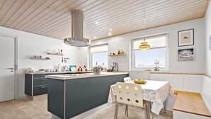 A modern kitchen with a central island, wooden ceiling, and large windows. - 3 bedroom pet friendly home in Ulfborg (Ulfborg)