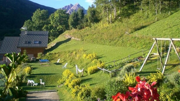 Paesaggio rurale con una casa, un'altalena e un sentiero che vi conduce.