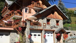 Una chalet a più piani con balconi, pareti in pietra e fioriere.