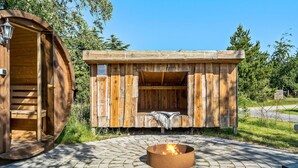 A wooden cabin with a fire pit and a bench.