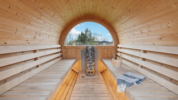 A sauna room with wooden walls and a large arched window.