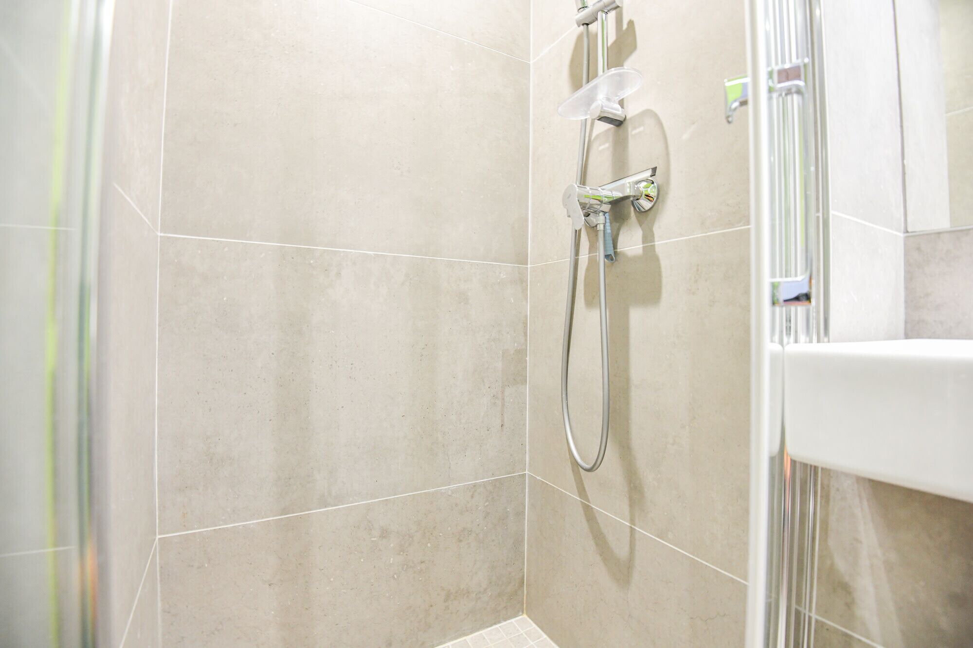 A bathroom with a shower area, tiled walls, and a visible shower head.