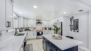Een moderne keuken met witte kastjes, een centraal eiland en een decoratief wandobject.