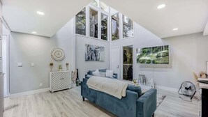 Een moderne slaapkamer met een vide en een groot raam, met uitzicht op groen.