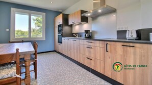 A modern kitchen with wooden cabinets, a built-in oven, and a coffee maker.