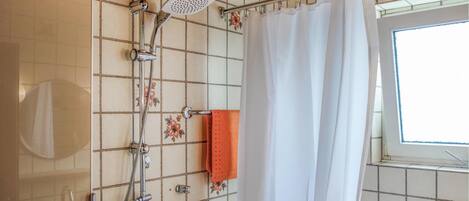 Ein Badezimmer mit Dusche, Handtuchhalter und Fenster.