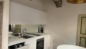 Una cucina compatta con mobili bianchi, forno a incasso e lavandino.