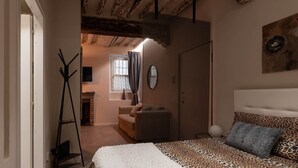 Una camera da letto con un letto, un divano, un caminetto e vista su un'altra stanza.