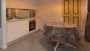 Una cucina compatta con forno a incasso, lavello e zona pranzo con tavolo e sedie.