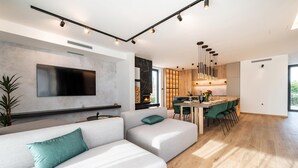 Una sala de estar moderna con un televisor de pantalla plana grande, una chimenea y un comedor con una mesa y sillas de madera.