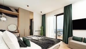 Un dormitorio moderno con cama, sofá, espejo y vistas al exterior.