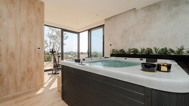 Un baño moderno con una bañera grande, suelo de madera y vistas al exterior.