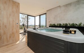 Une salle de bain moderne dotée d’une grande baignoire, d’un plancher en bois et offrant une vue sur l’extérieur.