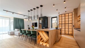 Una cocina moderna con una isla de madera, taburetes de bar, un televisor de pantalla plana y una estantería para vinos.
