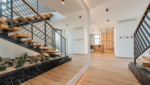 Un interior moderno con una escalera de madera, base de mármol y diseño minimalista.