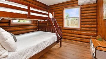 Ein Zimmer in einer Holzhütte mit Etagenbett, einem Fenster mit Blick und einer Holzkommode.