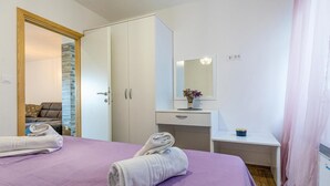 Una camera da letto con un letto, un armadio, una toeletta con specchio e un tavolino con un vaso di fiori.