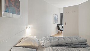 Een moderne slaapkamer met een bed, een stoel en kunstwerken aan de wanden.