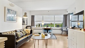 Een moderne woonkamer met een bank, een eettafel en uitzicht op de omgeving.