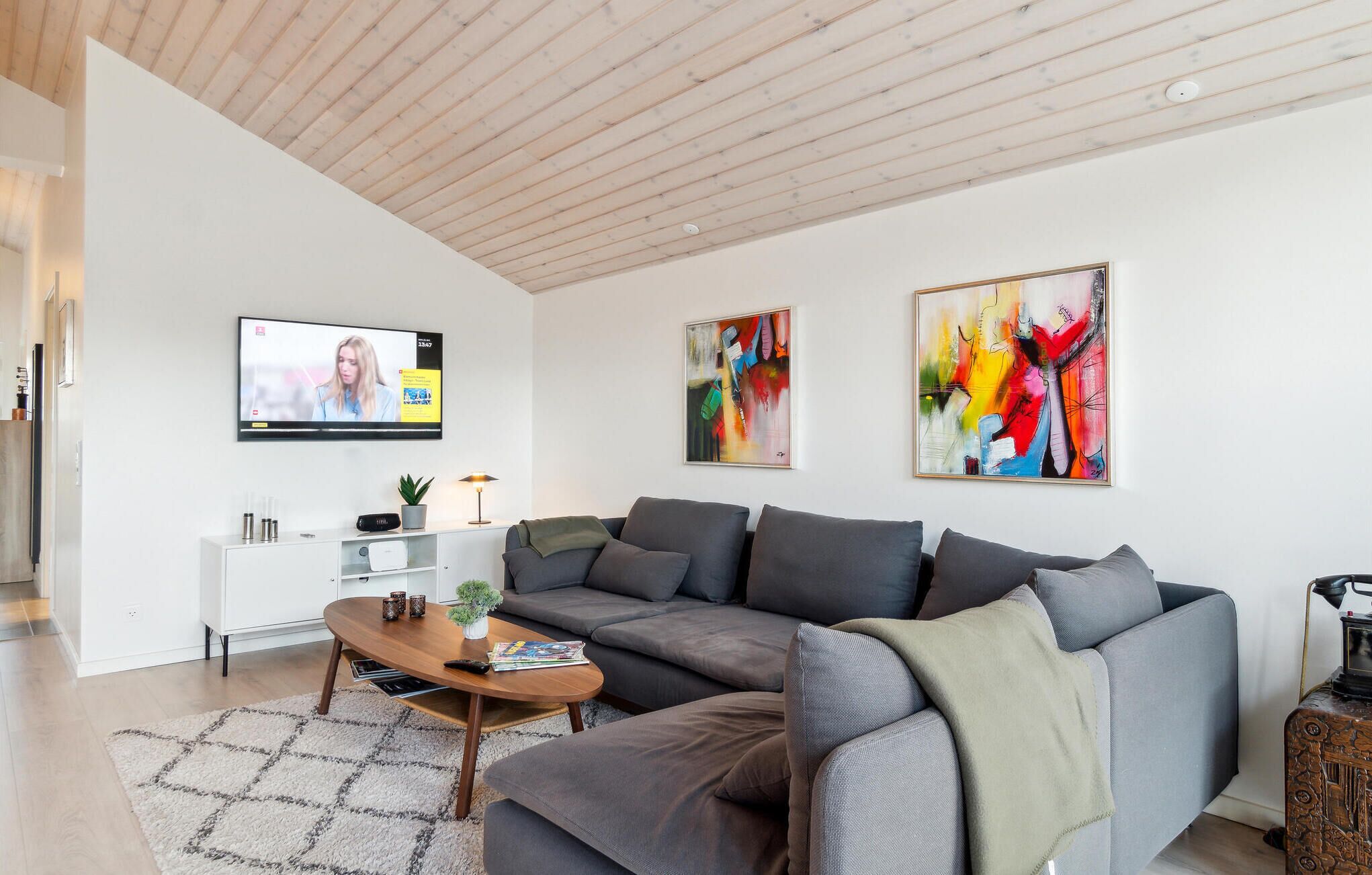 A modern living room with a sectional sofa, a coffee table, and two abstract paintings on the wall.