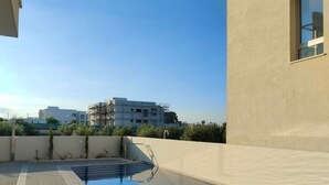 A rooftop swimming pool with a clear view of surrounding buildings. - Anchora___ (Paralimni)