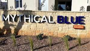 A stone wall with the text "MYTHICAL BLUE" and a small sign with "KKARMA". - Anchora___ (Paralimni)