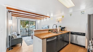 A modern kitchen with a wooden countertop, stainless steel appliances, and a view to the outside. - 5BR Beach House | Hot Tub, Game Room + Studio (Summerland)
