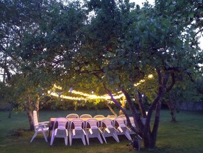 Ein Außenbereich mit Stühlen und Tischen unter einem Baum, geschmückt mit Lichterketten.