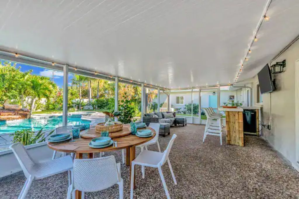 An outdoor dining area with a pool view, covered patio, and a bar area.