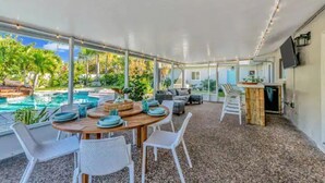 An outdoor dining area with a pool view, covered patio, and a bar area. - Pool, hot tub, putting green, pickleball, tiki bar, fire pit (Bradenton)