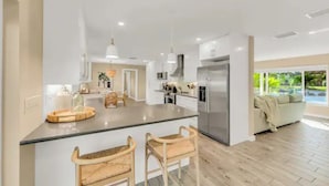 A modern kitchen with a central island, bar stools, and a large refrigerator. - Pool, hot tub, putting green, pickleball, tiki bar, fire pit (Bradenton)
