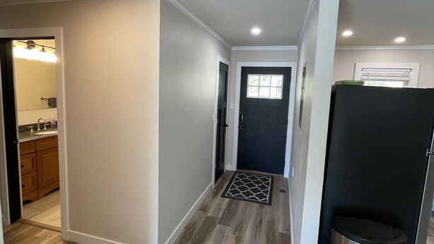 A hallway with wooden flooring, white walls, and a black door with a window. - Scenic 2BR by Pine Mountain - Ski Hill + Golf Course (Iron Mountain)